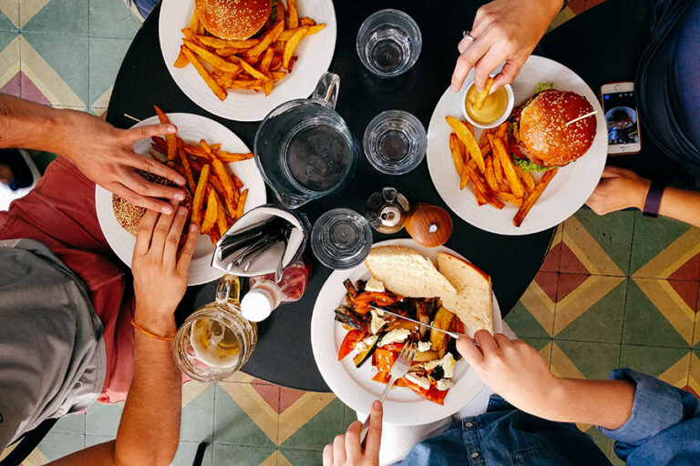 People gathered at a table eating burgers and fries.