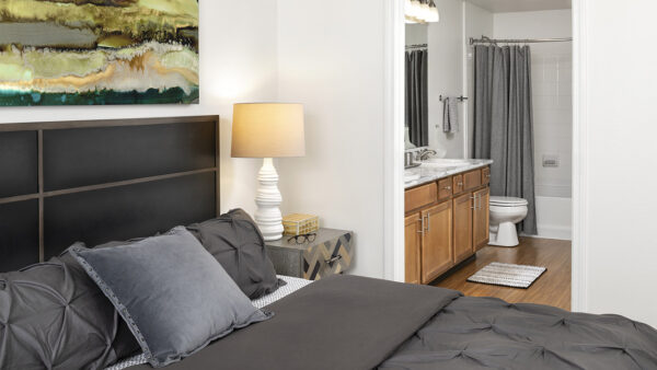 Spacious apartment bedroom with wood floors overlooking bathroom.