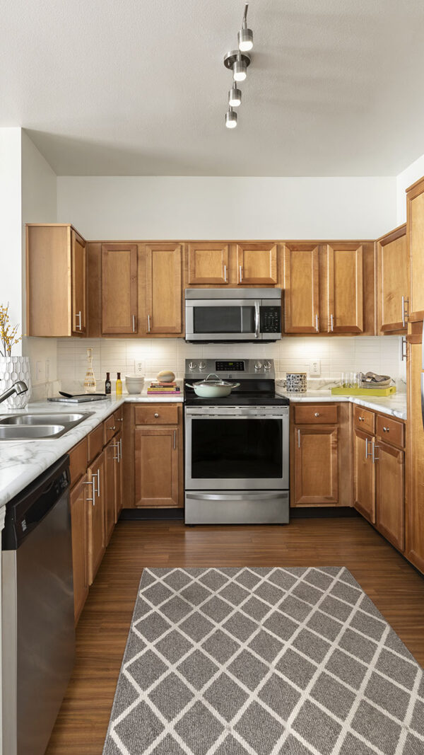 Apartment Kitchen with Stainless Steel Appliances, quartz counters and wood floors.