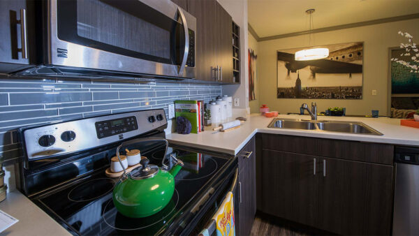 Apartment Kitchen with Stainless Steel Appliances, quartz counters and wood floors.