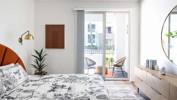 Spacious apartment bedroom with wood-style flooring and balcony access.