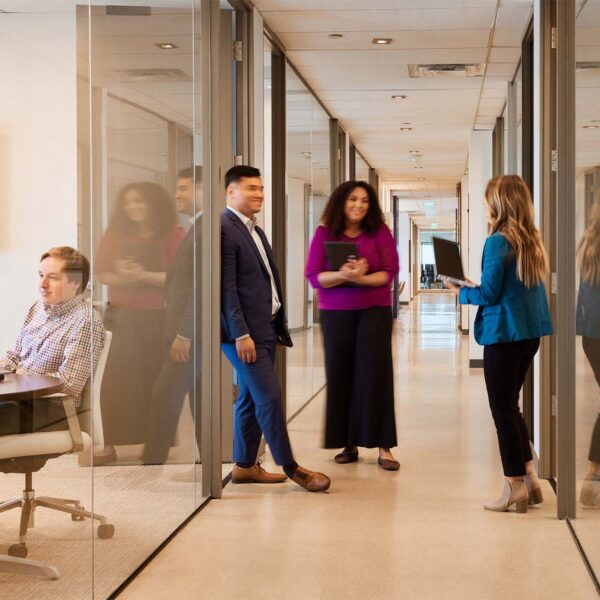 Griffis employees collaborating together in modern glass office hallway.
