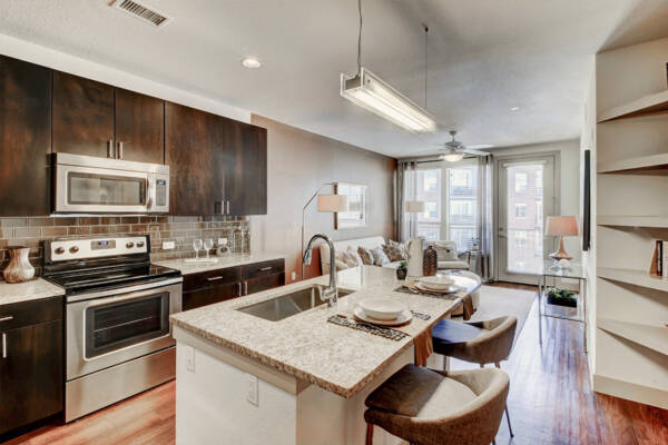 Apartment kitchen with stainless steel appliances, granite countertops and wood-style flooring.