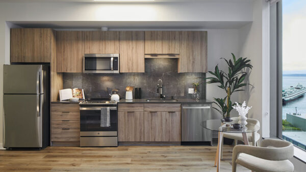 Apartment kitchen with wood cabinets, stone counters, and stainless steel appliances.