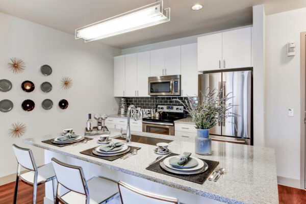Apartment kitchen with stainless steel appliances, granite countertops and wood-style flooring.