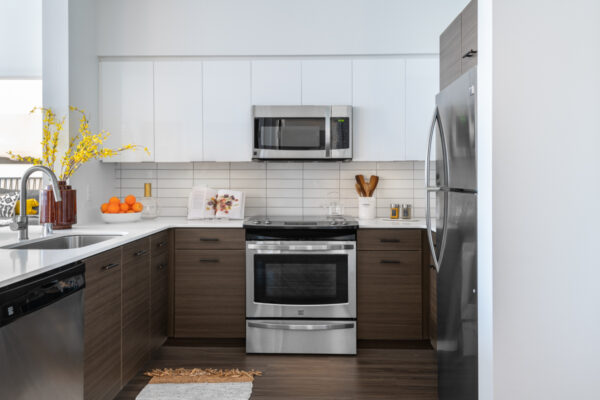 Apartment kitchen with stainless steel appliances, quartz countertops and wood-style flooring.