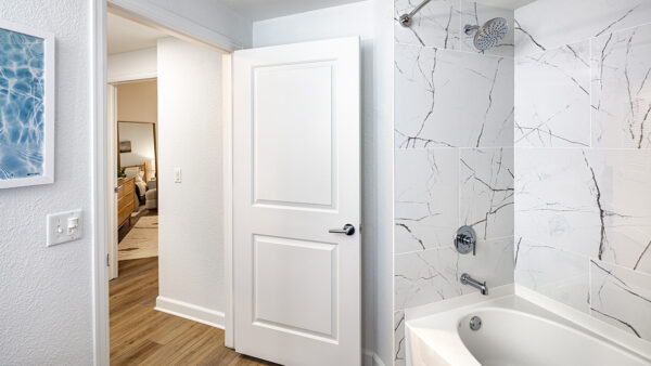 Apartment bathroom with large soaking tub and wood-style flooring.