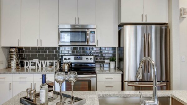Apartment kitchen with stainless steel appliances, granite countertops and wood-style flooring.
