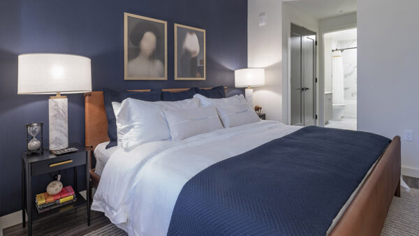 Spacious apartment bedroom with attached bathroom and wood-style flooring.