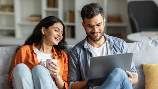 Resident couple smiling and sitting on couch in their apartment rental