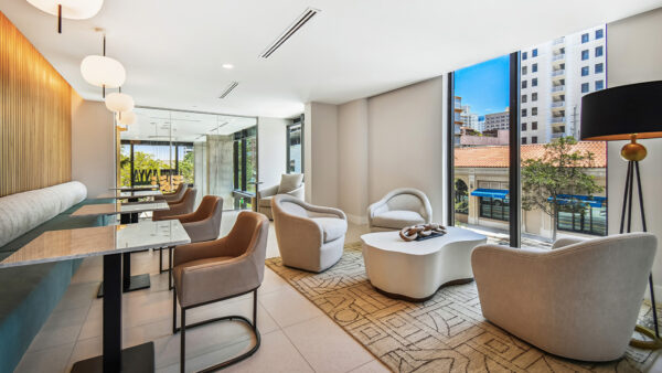 Griffis West Palm apartments coworking lounge with plush seating and floor to ceiling windows.