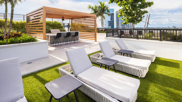 Griffis West Palm apartments rooftop deck with BBQ grill, gazebo, turf lawn, and lounge chairs.