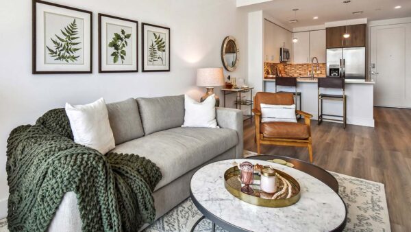 Griffis West Palm apartment living room with pattern rug, plush couch, framed artwork, and round tables.