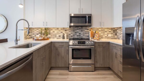 Griffis West Palm apartment kitchen with wood style floor and cabinets, quartz countertops, and stainless steel appliances.