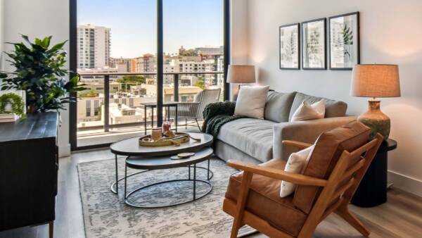 Griffis West Palm apartment living room with pattern rug, plush seating, framed art, and floor to ceiling window.