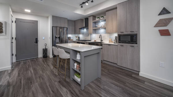 Griffis Edgemoor apartment kitchen with an island, gray cabinetry, and stainless steel appliances.