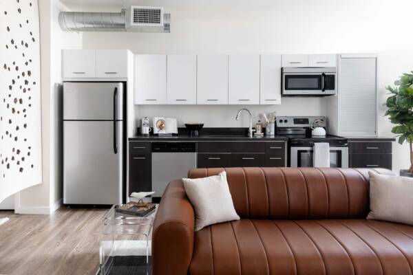 Griffis East Village apartment living area and kitchen with wood style floor and stainless steel appliances in San Diego, CA.